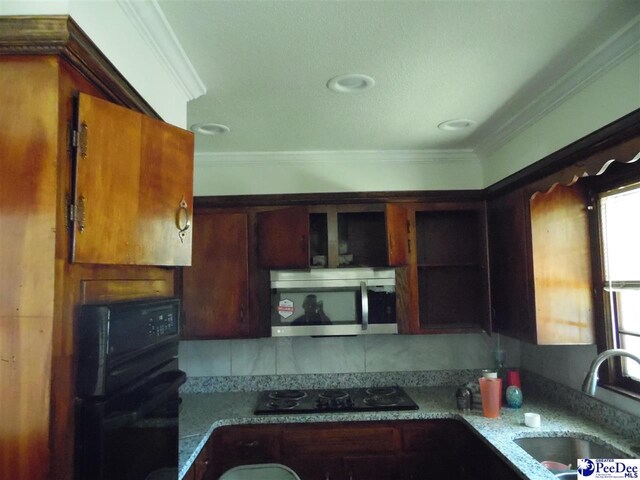 kitchen featuring ornamental molding, sink, dark stone counters, and black appliances