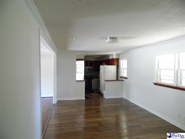 unfurnished living room featuring crown molding and dark wood-type flooring