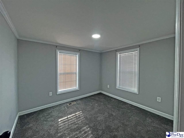 spare room featuring dark colored carpet and crown molding