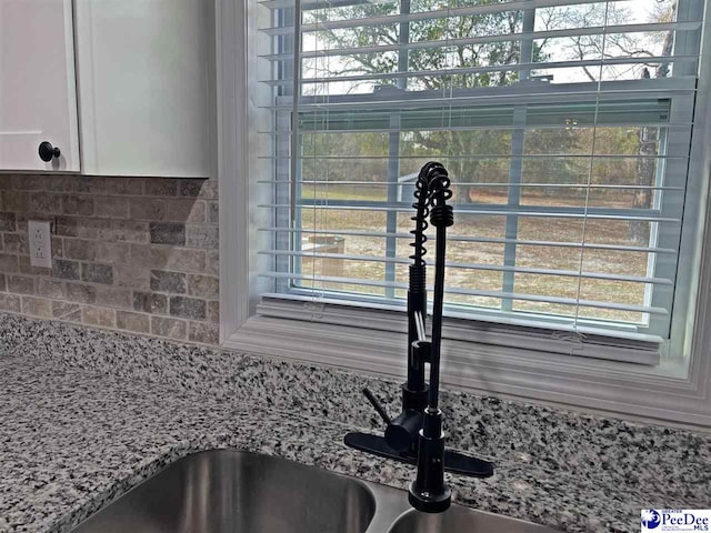 room details with sink, backsplash, and light stone countertops