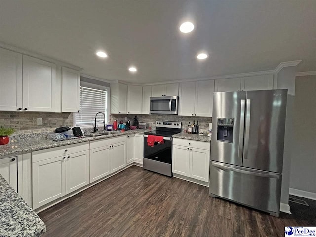 kitchen with appliances with stainless steel finishes, sink, white cabinets, dark hardwood / wood-style flooring, and light stone countertops