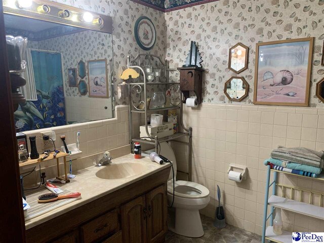 bathroom featuring vanity, toilet, and tile walls