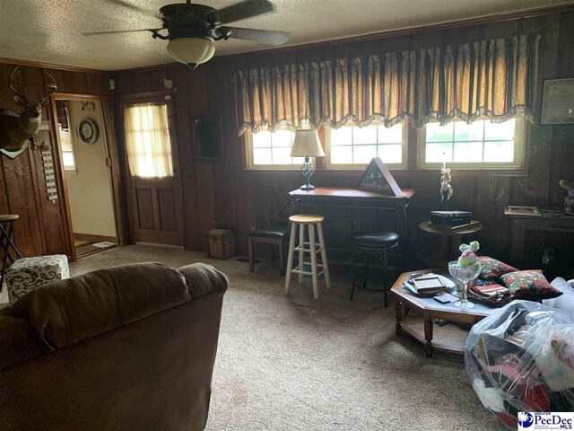 living room with carpet floors, a textured ceiling, and wood walls