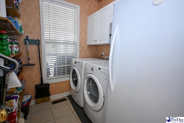 laundry area with independent washer and dryer, cabinets, and light tile patterned floors