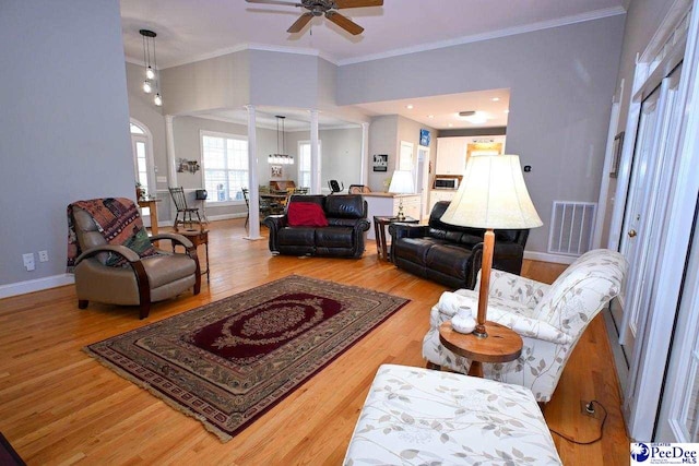 living room with decorative columns, wood-type flooring, ceiling fan, and crown molding