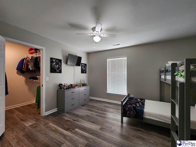 bedroom with a spacious closet, visible vents, a ceiling fan, dark wood-type flooring, and baseboards