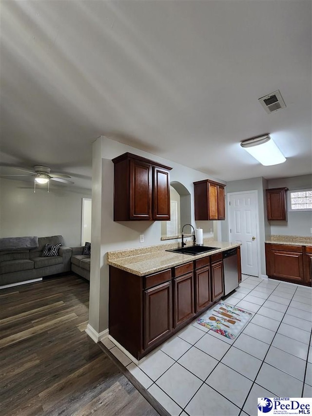 kitchen with a sink, arched walkways, open floor plan, visible vents, and dishwasher