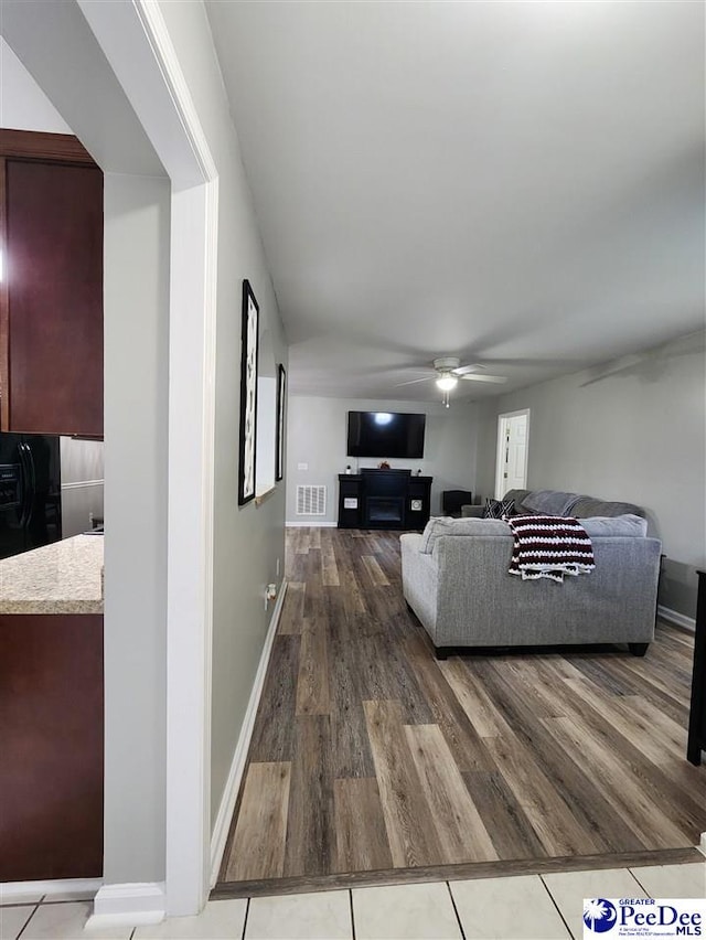 living area with baseboards, a ceiling fan, wood finished floors, and visible vents