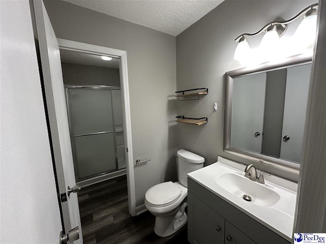 bathroom featuring hardwood / wood-style floors, toilet, a textured ceiling, vanity, and walk in shower