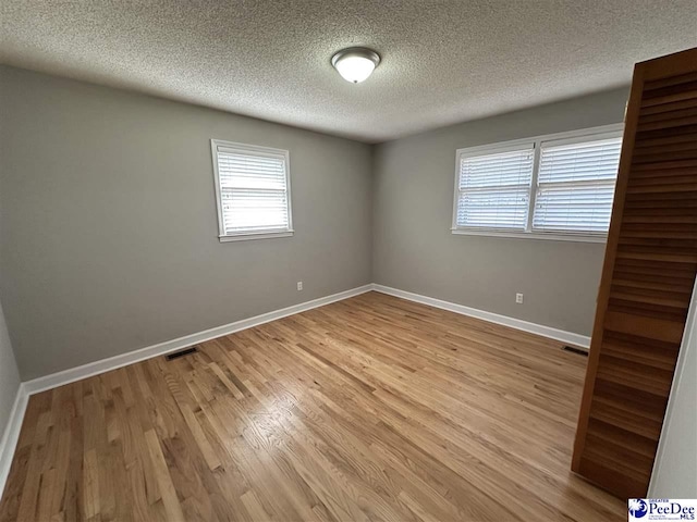 spare room with light hardwood / wood-style flooring and a textured ceiling