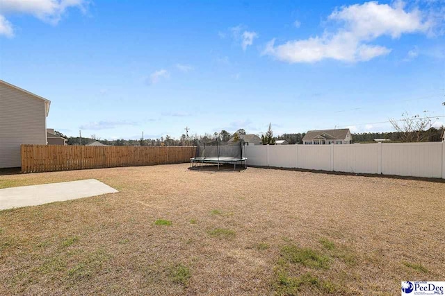 view of yard with a trampoline and a fenced backyard