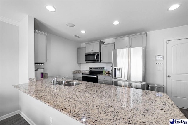 kitchen featuring recessed lighting, a sink, appliances with stainless steel finishes, gray cabinets, and light stone countertops