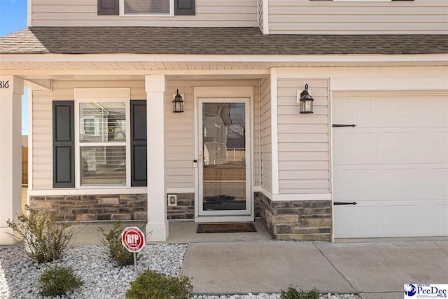 doorway to property featuring a shingled roof, stone siding, covered porch, and an attached garage