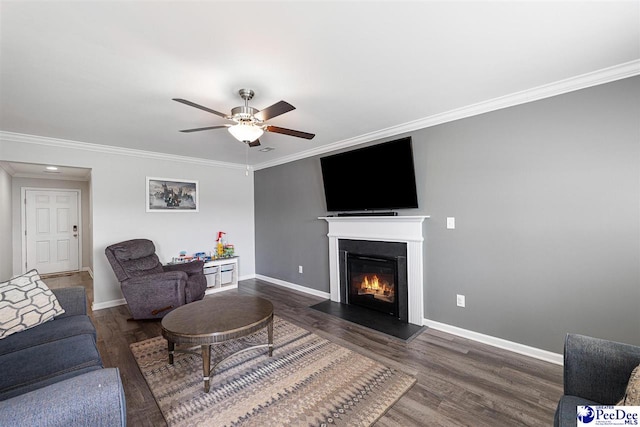 living room featuring a glass covered fireplace, dark wood-style flooring, crown molding, and baseboards