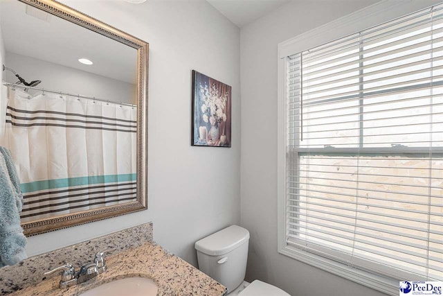 bathroom featuring a shower with shower curtain, vanity, and toilet