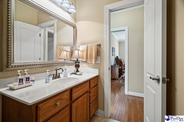 bathroom with ornamental molding, vanity, and hardwood / wood-style floors