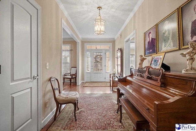 entrance foyer with ornamental molding, light wood-type flooring, and a notable chandelier