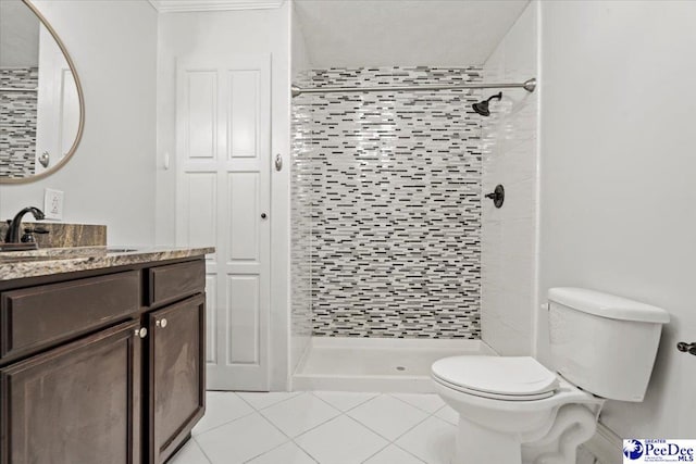 bathroom with vanity, a tile shower, tile patterned floors, and toilet