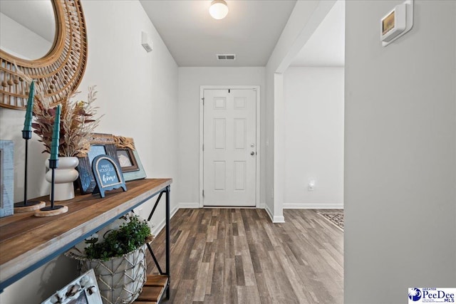 foyer entrance featuring visible vents, baseboards, and wood finished floors