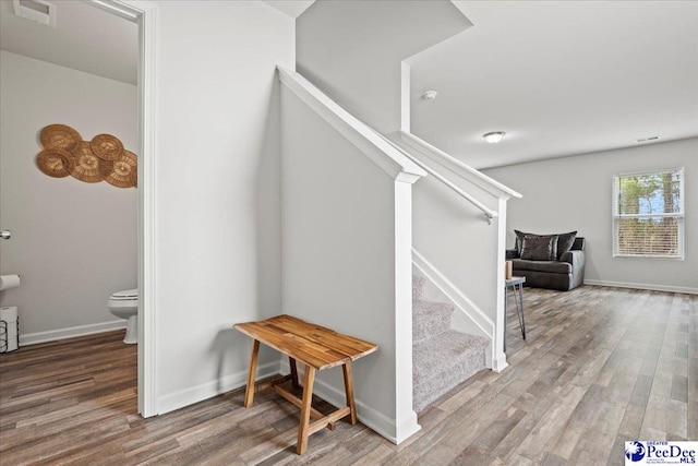 staircase featuring wood finished floors, visible vents, and baseboards