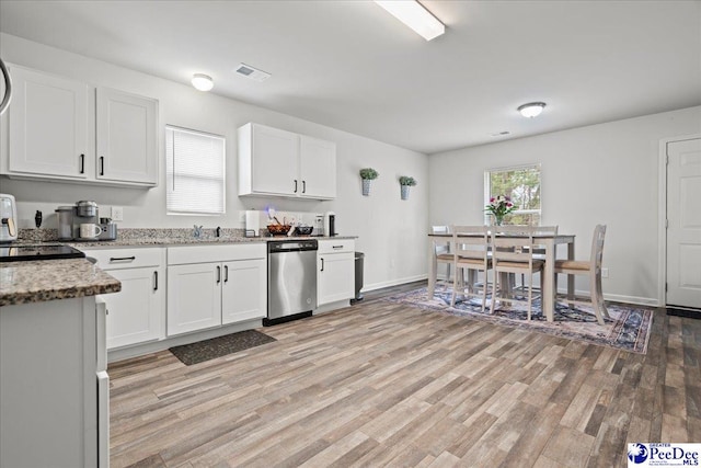 kitchen with light stone counters, visible vents, light wood-style flooring, stainless steel dishwasher, and white cabinets