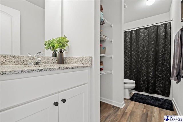 bathroom with toilet, baseboards, wood finished floors, and vanity