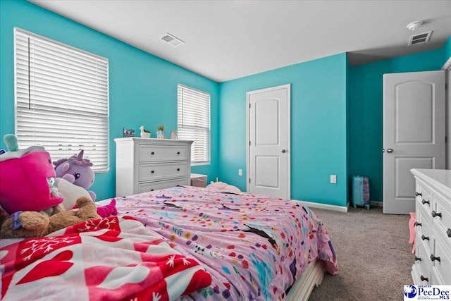 carpeted bedroom featuring visible vents, baseboards, and multiple windows