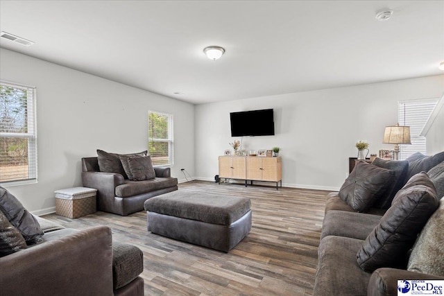 living area featuring wood finished floors, visible vents, and baseboards