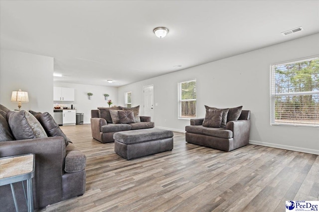 living area with plenty of natural light, light wood-type flooring, and visible vents