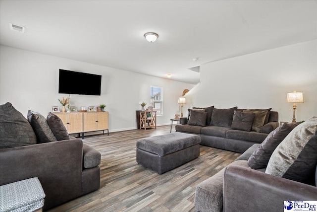 living room with visible vents, baseboards, and wood finished floors