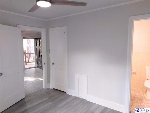 empty room with ornamental molding, wood-type flooring, tile walls, and ceiling fan