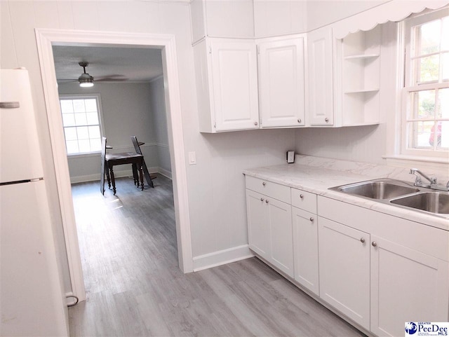 kitchen featuring white fridge, sink, white cabinets, and plenty of natural light