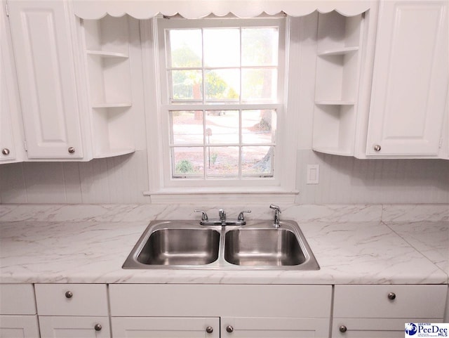 kitchen featuring light stone countertops, sink, and white cabinets