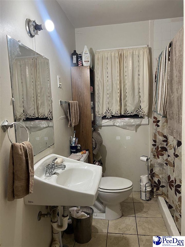 bathroom featuring tile patterned flooring, sink, toilet, and walk in shower