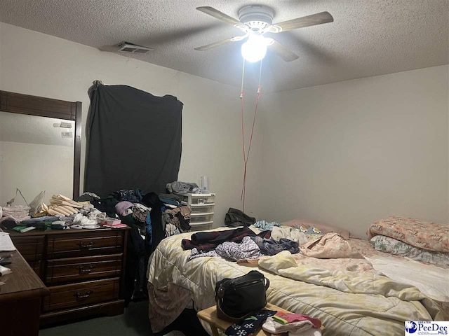 bedroom with ceiling fan and a textured ceiling