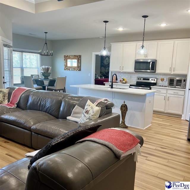 living room with light wood finished floors, a notable chandelier, recessed lighting, and a toaster