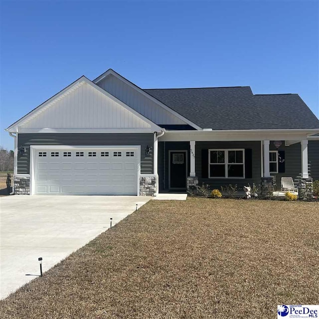 craftsman-style home with stone siding, covered porch, an attached garage, and concrete driveway