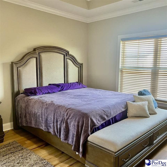 bedroom featuring visible vents, light wood-type flooring, baseboards, and ornamental molding