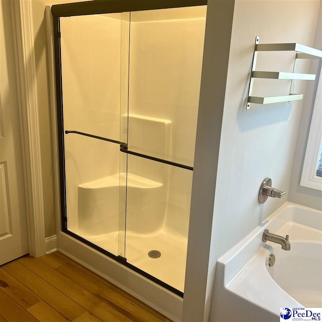 bathroom with an enclosed shower, wood finished floors, and a bath