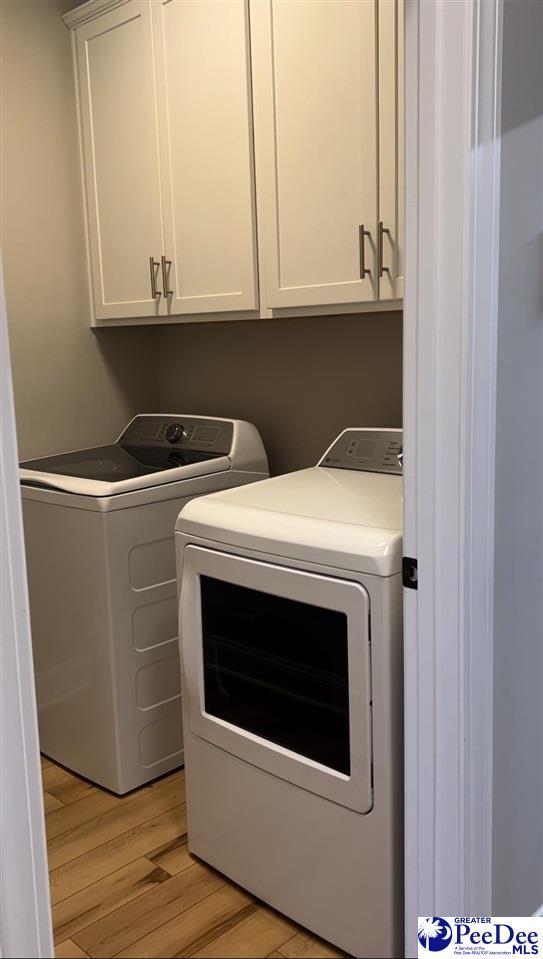 laundry area with cabinet space, independent washer and dryer, and light wood-style flooring