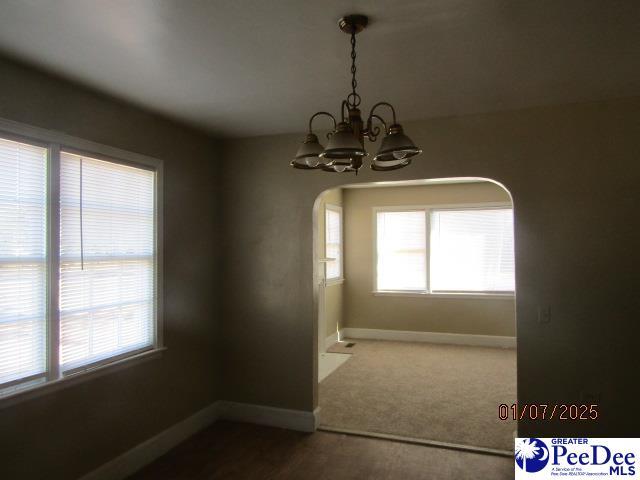 unfurnished dining area featuring a chandelier