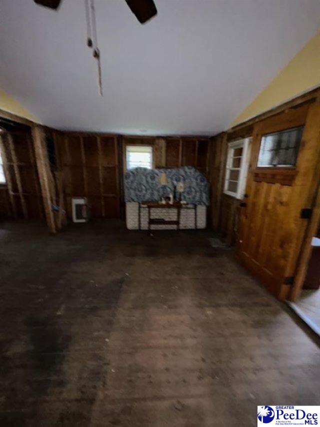 miscellaneous room featuring wood walls, heating unit, and ceiling fan