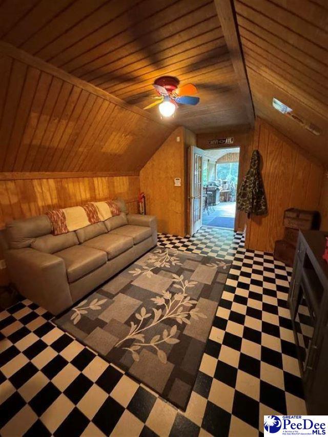 bonus room with lofted ceiling, ceiling fan, wood walls, and wood ceiling