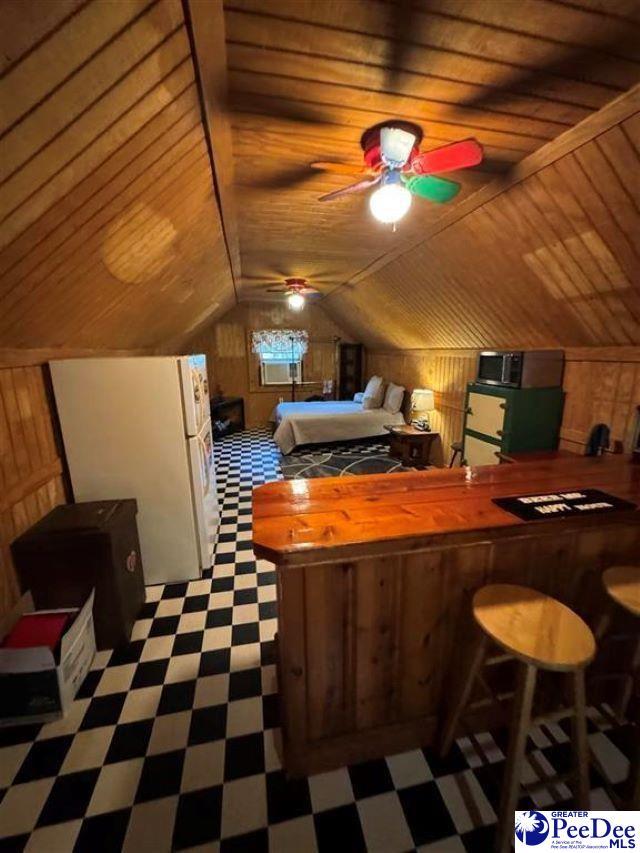 bedroom featuring freestanding refrigerator, wood ceiling, wood walls, and tile patterned floors