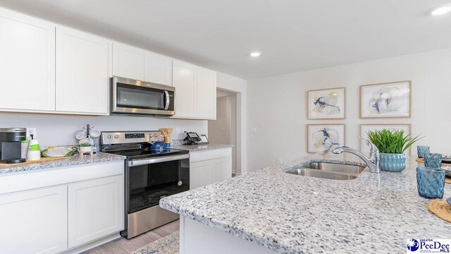 585 Strawberry Field Way, Galivants Ferry, SC 29544 - kitchen featuring stainless steel appliances, white cabinets, light wood-style floors, light stone countertops, and recessed lighting