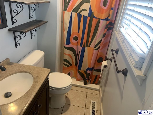 bathroom featuring tile patterned floors, vanity, toilet, and walk in shower