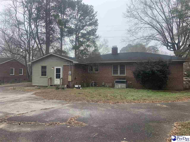 ranch-style home with central AC unit and a front yard