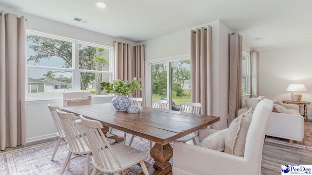 dining space with baseboards, light wood-style floors, and visible vents