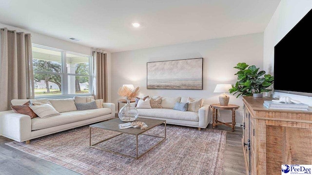living room with recessed lighting, visible vents, and wood finished floors