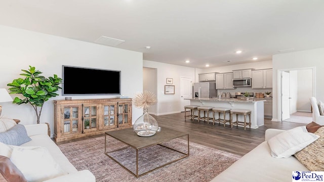 living room featuring baseboards, recessed lighting, and dark wood-type flooring